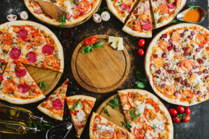 Many kinds of tasty pizzas on black background. Flatlay. Copy space